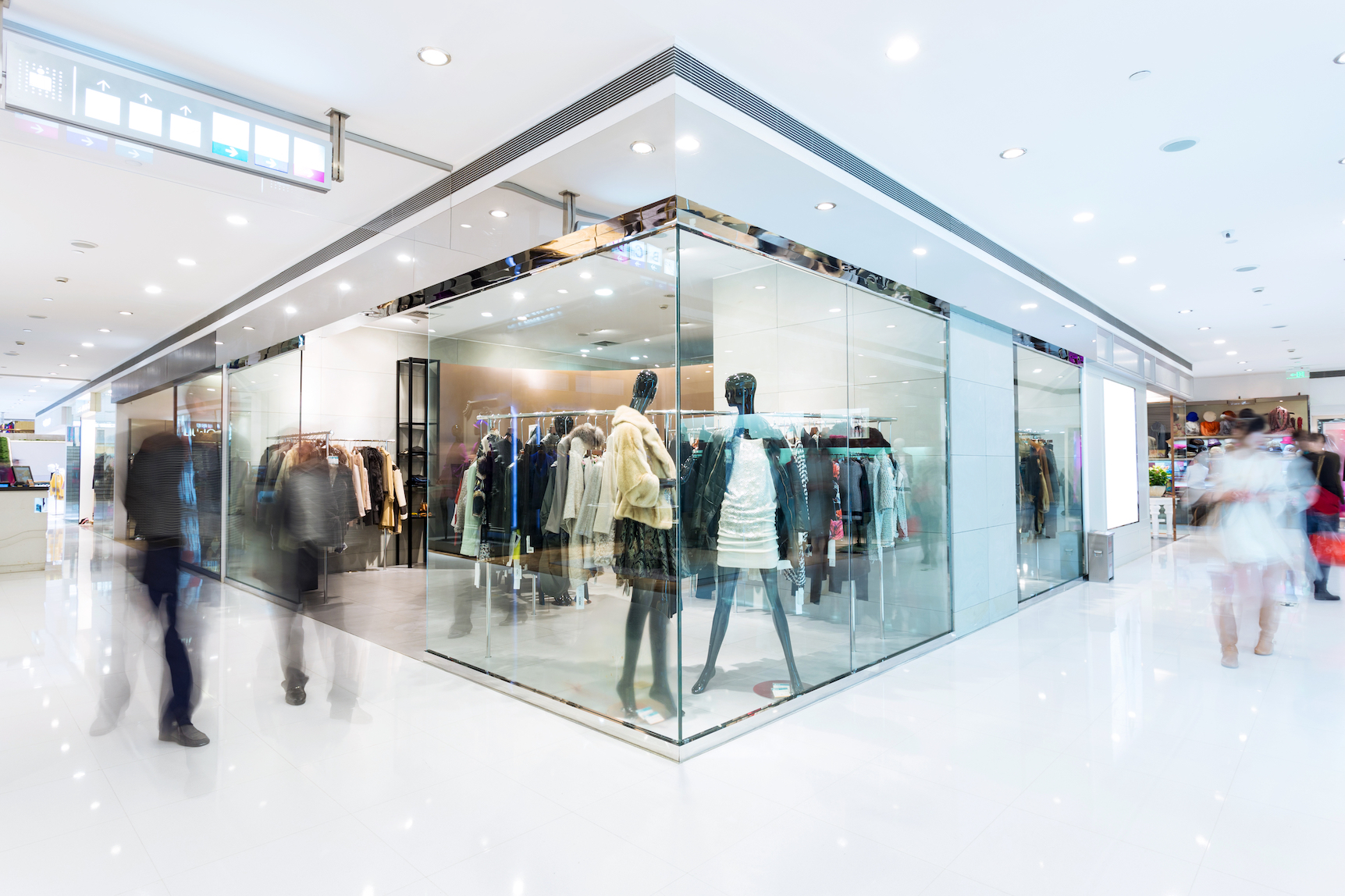 Shoppers passing a store window display. Smart glass signage can help retailers to make better use of their space for advertising purposes.